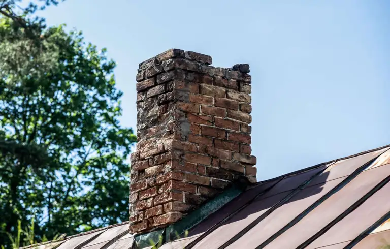 Brick chimney on a sloped roof before removal in Toronto