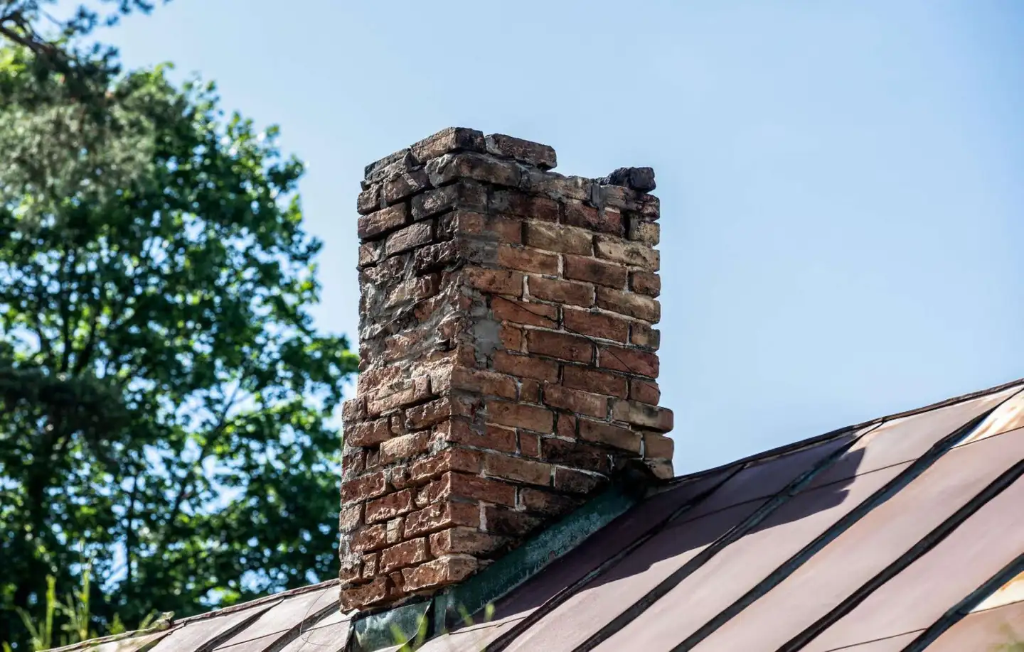 Brick chimney on a sloped roof before removal in Toronto